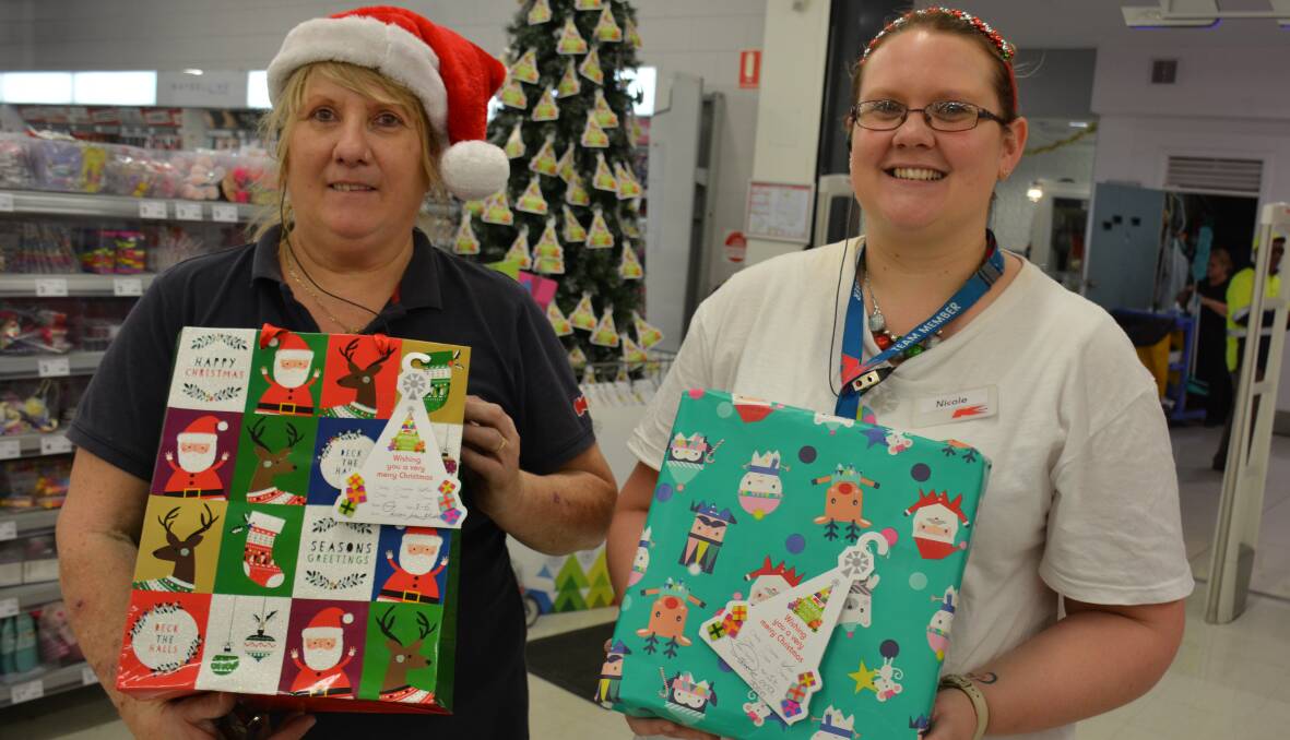 Mount Isa Kmart employees Vicki Drake and Nicole Hall gather presents donated under the wishing tree. Gifts go to the Salvation Army's Christmas Appeal. 