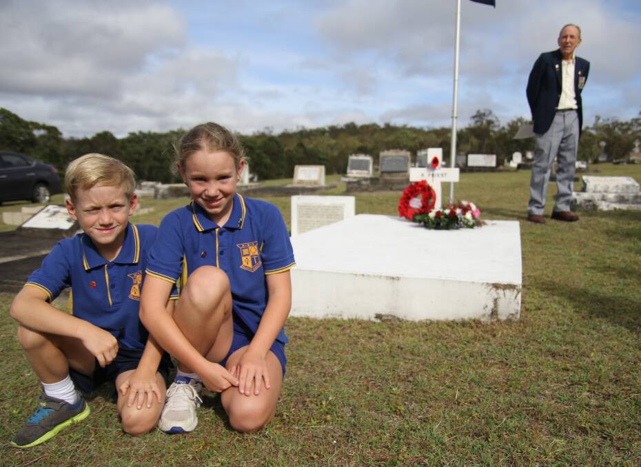 Herberton siblings Dayne, 8, and Emma, 10, Ross at the gravesite of Reverend White, while Wayne Linwood looks on.
