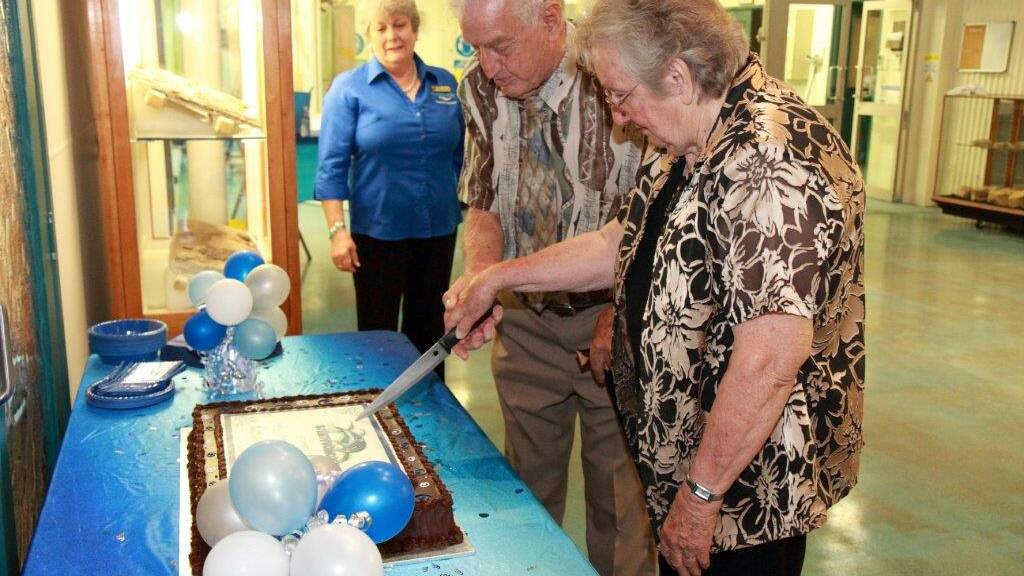 Long-time museum associates Val Bennett and Len Smith cut the Kronosaurus Korner's 20th birthday cake while Richmond shire councilor June Kuhl looks on.