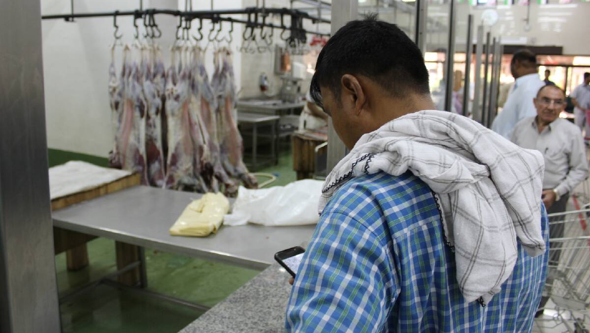 BUSY PERIOD AHEAD: A customer uses his smartphone to take a photo of his purchased Australian carcase at a Dubai abattoir in July.