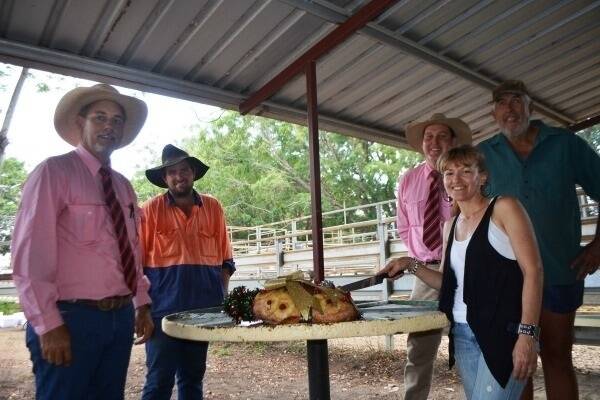 Mark Peters (left) and Brian Rowling (middle), Elders Mareeba, stood watch as top-price vendor Maria Posselt, Geria Brahman Stud, Walkamin, continued a long-held tradition by carving the Christmas ham while top-price buyer Ben Finlayson, Ingham, and father Jeff looked on during the 2013 sale.