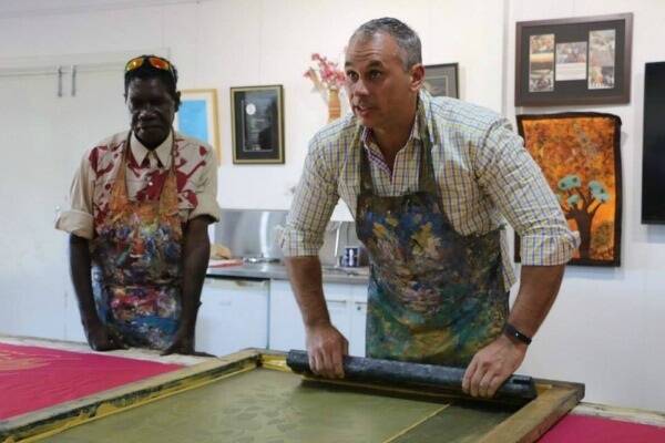 NT Chief Minister Adam Giles gets a lesson in fabric screenprinting from Injalak Arts Centre co-manager Isaiah Nagurrgurrba during the opening of the interpretative arts section at the centre. 