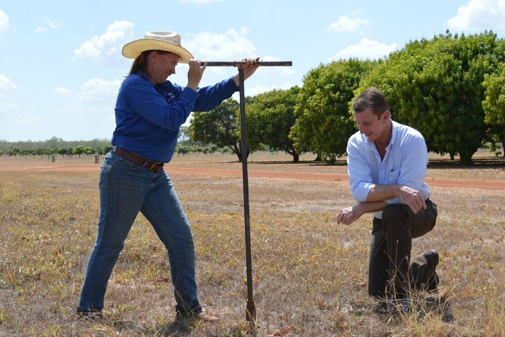 After announcing a $426,000 program to determine how long CGMMV lives in local soils, Primary Industry and Fisheries Minister Willem Westra van Holthe helps Katherine Research Station plant industries technical officer Teagan Alexander collect a soil sample.