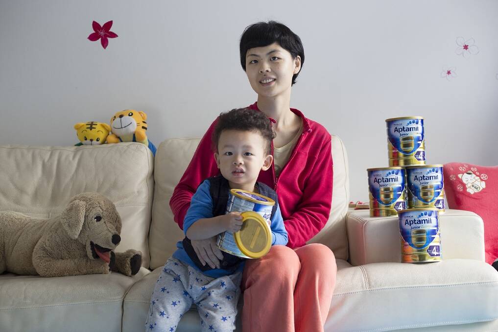 Cindy Chen, at home with her son in Shanghai, China, with cans of baby milk formula bought from Australia. Photo: Jonathan Browning