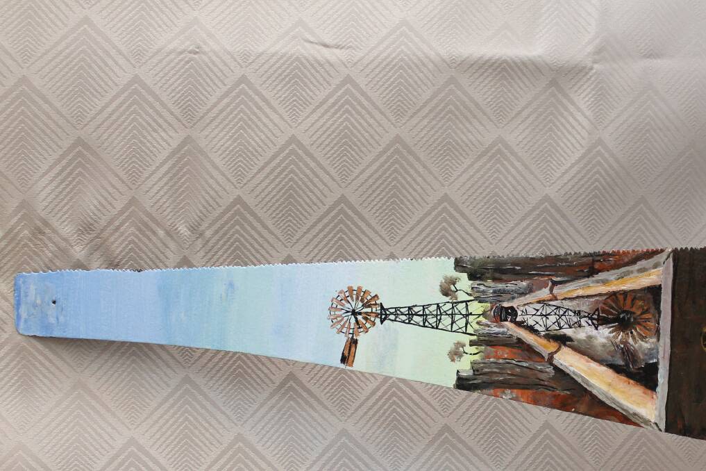 A windmill painted directly onto an old saw. 
