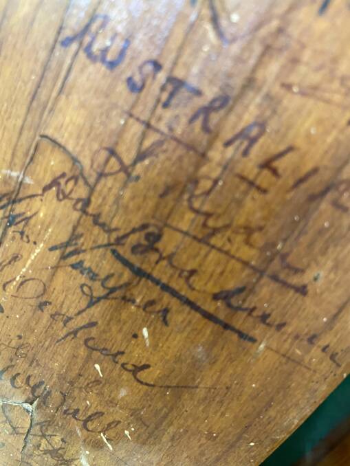 Don Bradman's signature preserved on the bat, along with those of his team members and the England team.