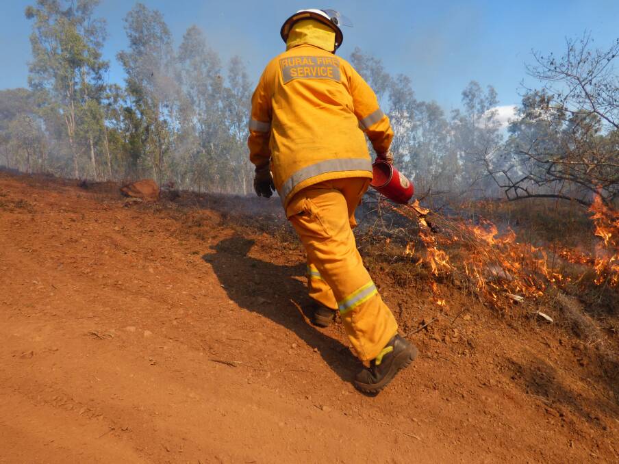 A Rural Fire Brigade volunteer burning back with a drip torch. Picture - Justin Choveaux.