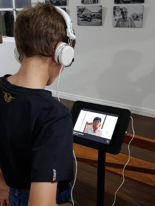 A young exhibition attendee uses headphones to listen to one of the iPad presentations.