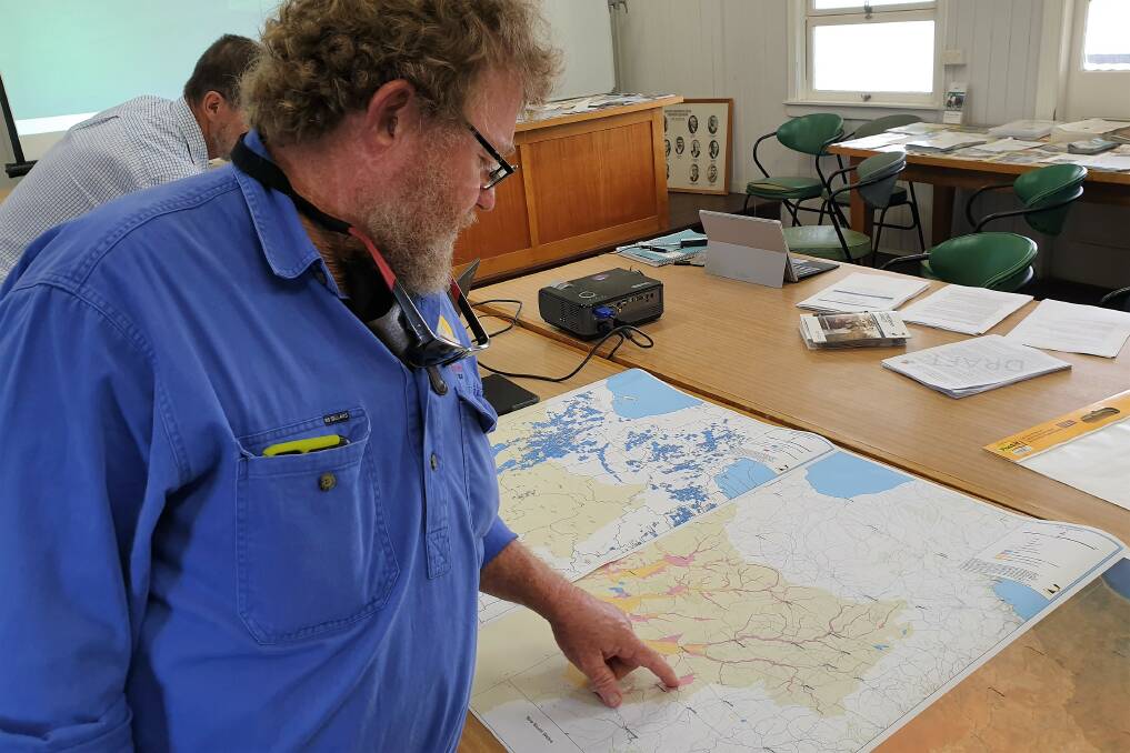 Desert Channels Queensland staff member Peter Spence pores over the map of the proposed changes to the Lake Eyre Basin management plan.