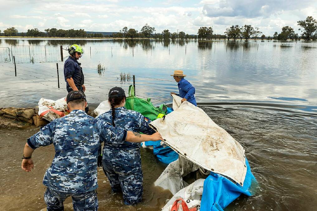 Aircraftman Kade Kennaway and Leading Aircraftwoman Anya Morris assist Stephen and Margaret Redfern in retaining a burst water levy on their property, thirty kilometres west of Forbes, during Operation Flood Assist. Picture: David Cotton, ADF