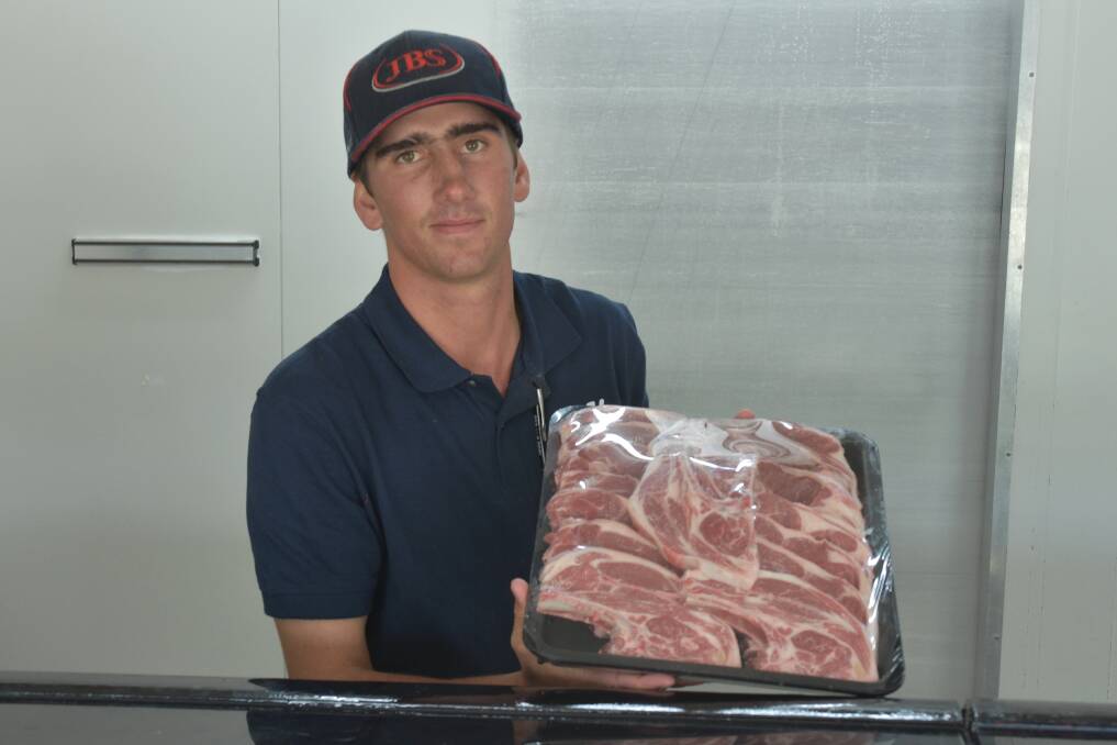 6TK Butchery's fully qualified butcher, Sam Monds, holding a tray of freshly cut meat in the store. 