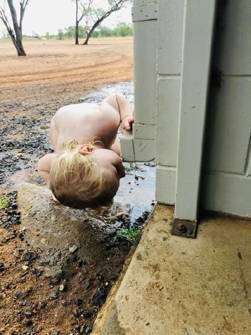 Pippa Roselt, 18 months, drinks fresh rainwater from the drain at Pialah Station, north of Richmond. Photo - Georgie Roselt.